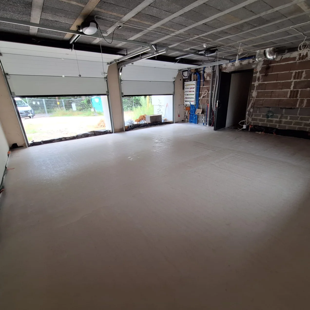 Wylewki anhydrytowe wykonane w przestronnej hali w stanie surowym z otwartymi bramami garażowymi