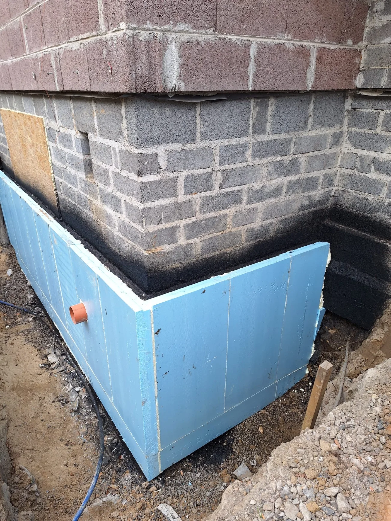 Izolacje fundamentu z niebieskich płyt styropianowych i bitumiczna powłoka przeciwwilgociowa