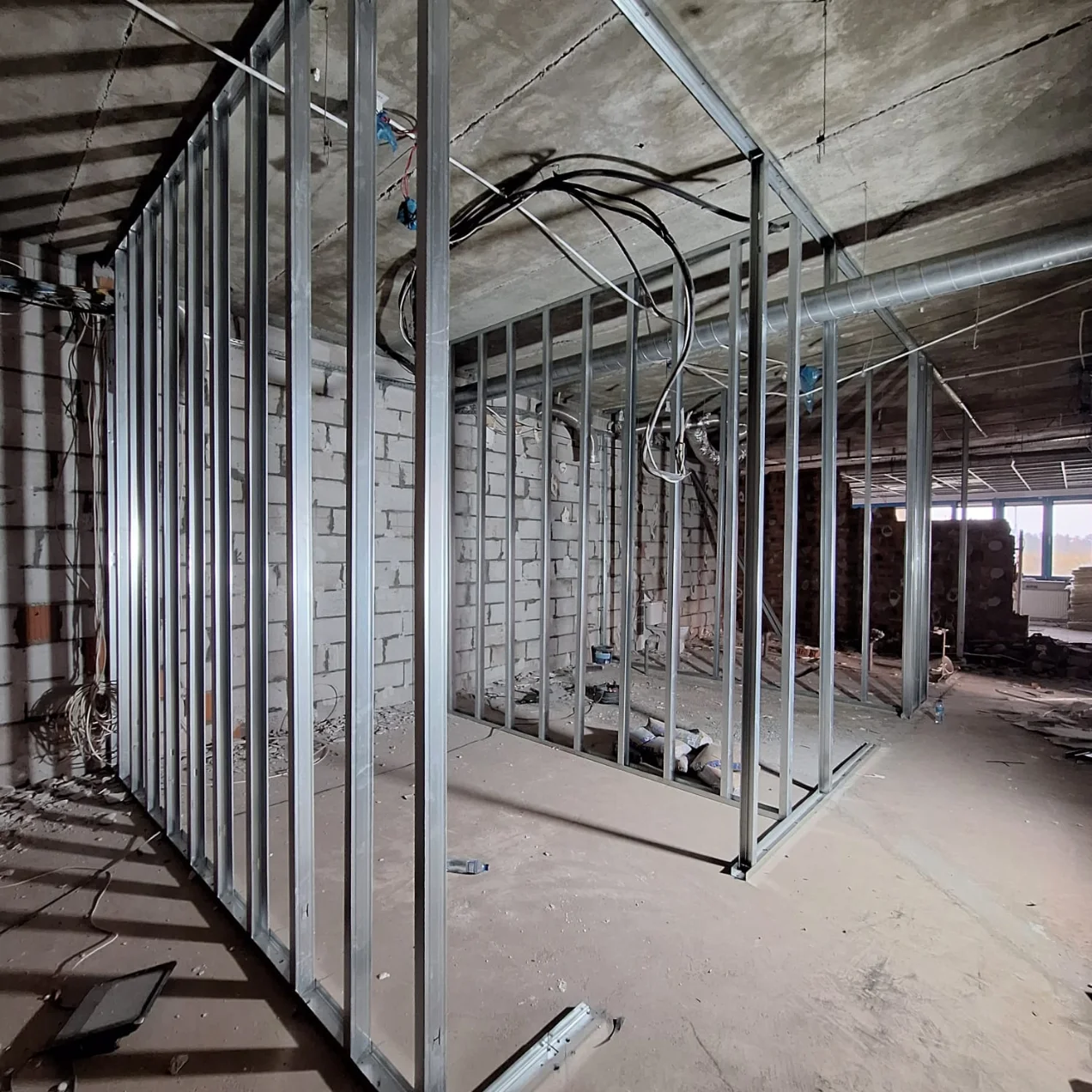 Montaż ścianek działowych z metalowych profili w surowym wnętrzu budynku