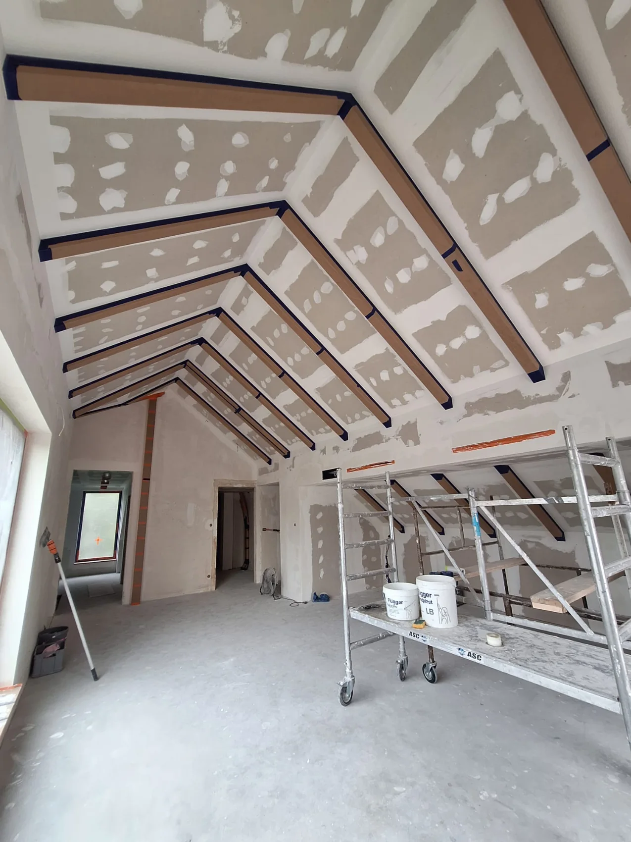 Wnętrze poddasza z zamontowanymi profilami sufitowymi, rusztowaniem i płytami gipsowo-kartonowymi Sucha zabudowa