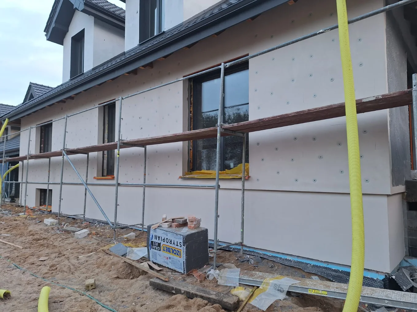 Elewacja budynku w trakcie montażu płyt termoizolacyjnych z rusztowaniem – Ocieplenia budynków