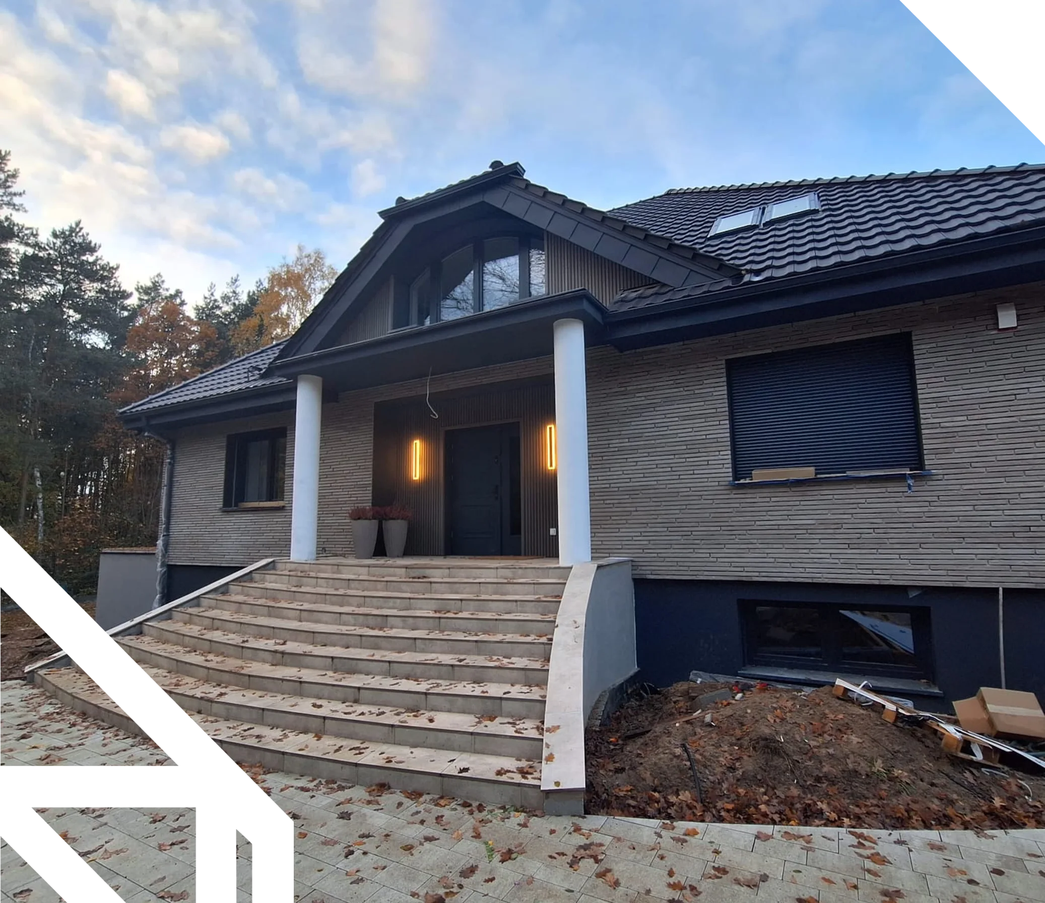 Wejście do nowo wybudowanego domu z szerokimi schodami, kolumnami i wykończoną elewacją Budowa domu